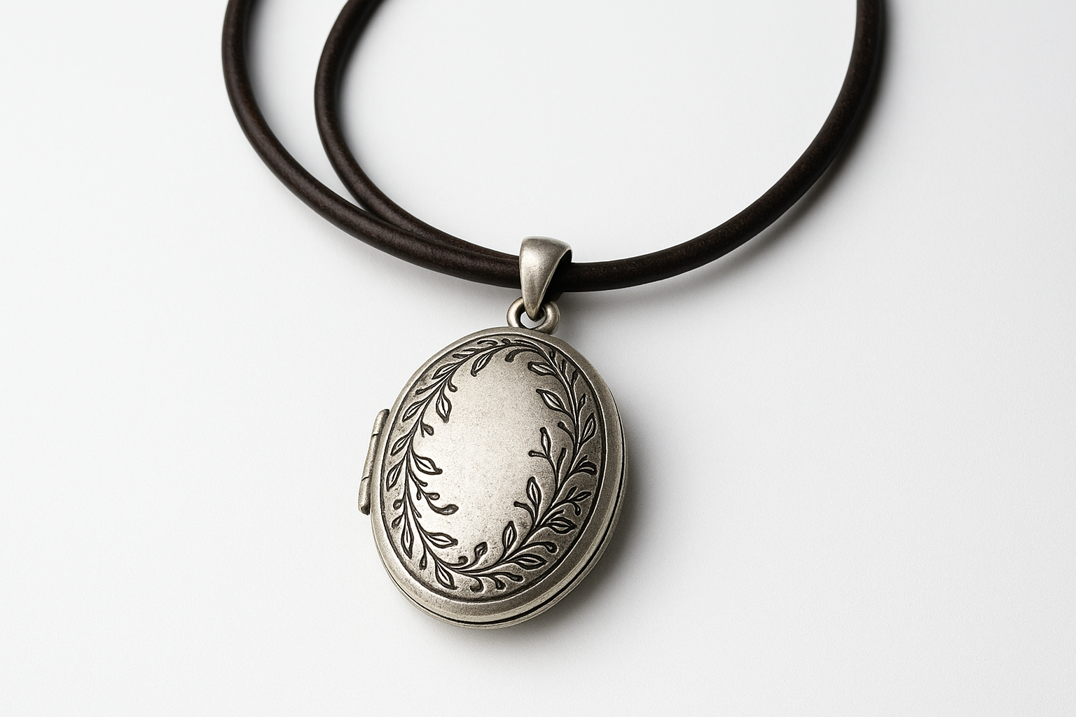 Oval silver pendant with vine engravings on dark brown leather cord